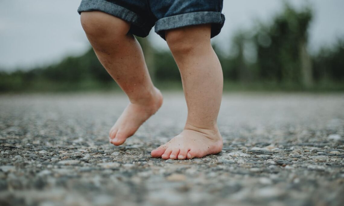 Niño andando descalzo sobre suelo con piedras
