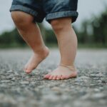 Niño andando descalzo sobre suelo con piedras