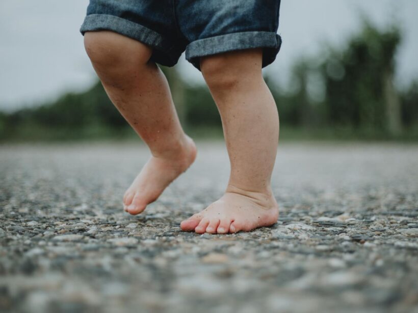 Niño andando descalzo sobre suelo con piedras